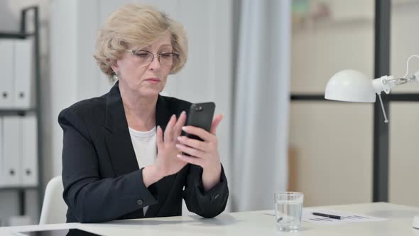 Old Businesswoman Using Smartphone at Work