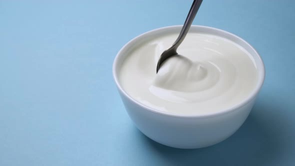 Bowl of sour cream on blue background, greek yogurt