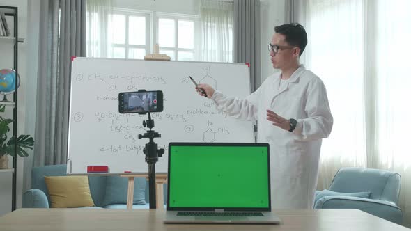 Asian Male Teacher With Green Screen Laptop While Teaching Chemist Online At Home