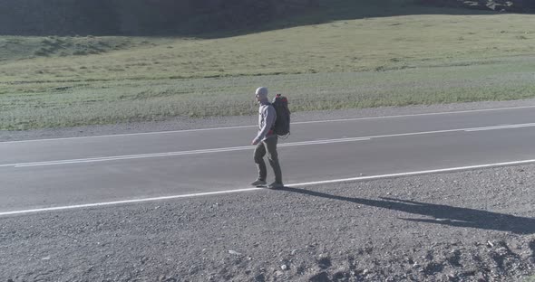 Flight Over Hitchhiker Tourist Walking on Asphalt Road