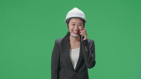 Smiling Asian Female Engineer Celebrating After Talking On Smartphone In The Green Screen Studio