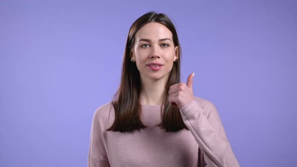 Pretty Woman Showing Thumb Up Like Sign Over Violet Studio Background