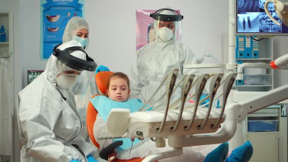 Pediatric Dentist in Protective Suit Lighting the Lamp Until Examination