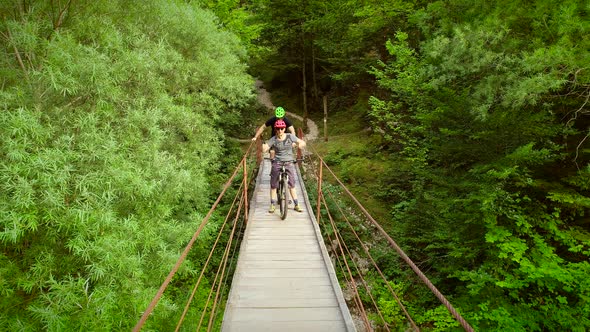 Aerial view of a couple standing with bicycles in the middle of the bridge.