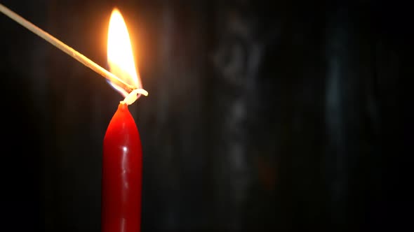 Red Candle Are Set Fire with Long Wooden Match on Dark Wooden Wall Background