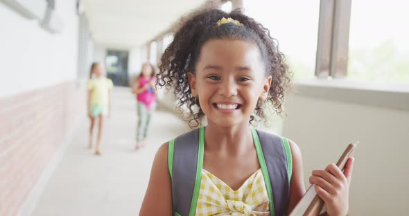 Video of happy biracial girl standing on school corridor