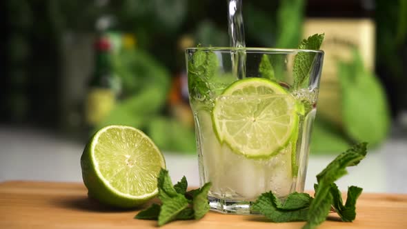 Soda Slow Motion Fill Glass with Ice. Fanta Soda Drink. Glass Stand on Wooden Plate with Lime and