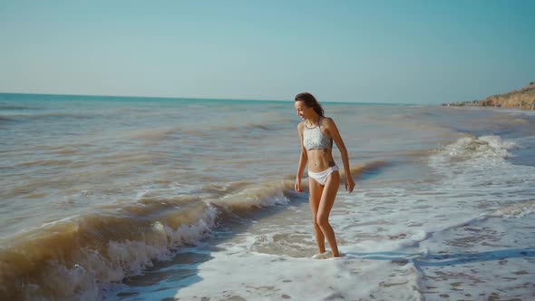 Happy Carefree Slender Woman with Beautiful Fitbody Running Along Seashore of Sea with Waves After