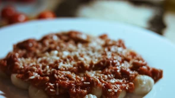 Gnocci with Tomato Sauce Being Sprinkled with Parmesan