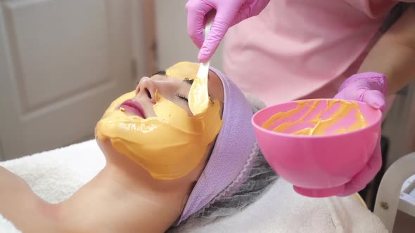 Face peeling mask. Woman getting facial care by beautician at spa salon. Cosmetologist job.