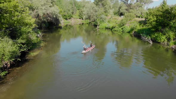 An Aerial View. A Man and a Woman Swim on a Kayak on a River.