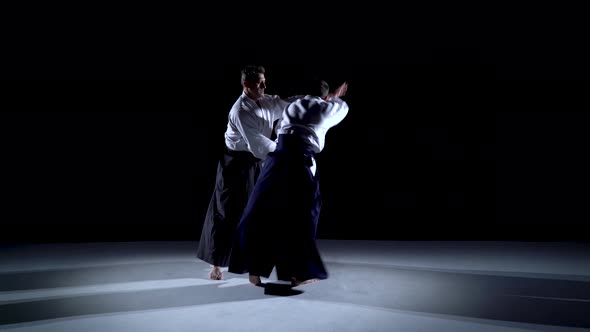 Two Masters Participants of the Training in Special Clothes of Aikido Hakama Work Out the Methods of