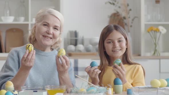 Happy Grandma and Granddaughter Holding Easter Eggs and Posing for Camera