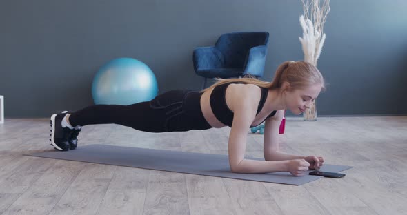 Strong Girl Doing Plank , Using Stopwatch on Her Phone