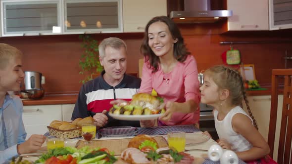 Mother Brings Baked Chicken Dish From Oven at Family Thanksgiving Birthday Celebration in Kitchen