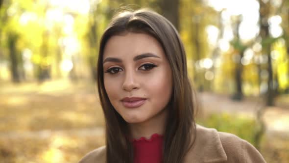 Close Happy Look at Camera of Beautiful Browneyed Girl in Autumn Sunny Park