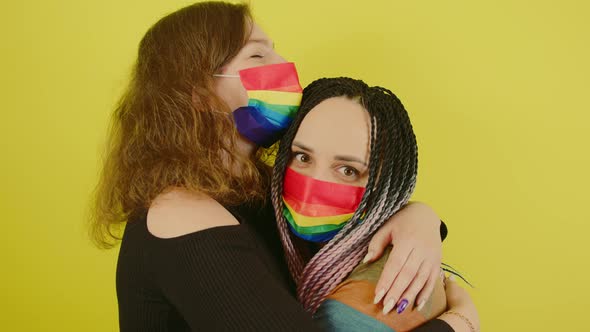 Lesbian Couple in Rainbow Masks Embracing in Studio