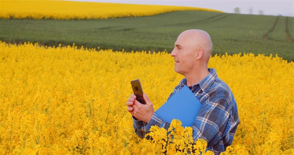 Confident Male Botanist Photographing Oilseeds On Field