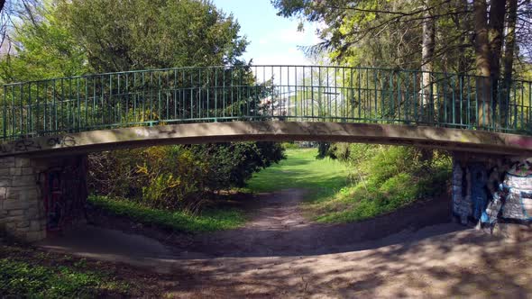 Between trees along a path down through footbridge. Great aerial view flight fly backwards drone foo