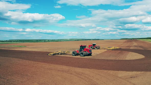 Working Tractors Ride on a Field, Plowing.