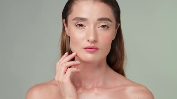 Beautiful Young Woman with Clean Fresh Skin Standing Over Light Grey Background