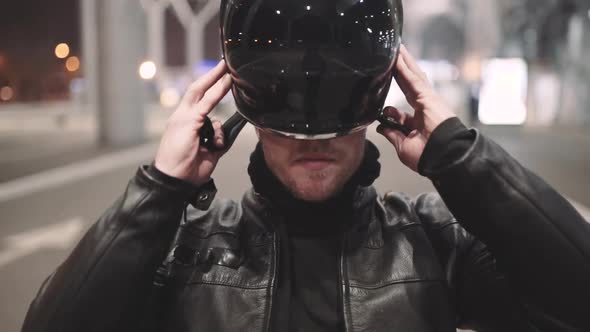 Caucasian Man Motorcyclist Wears a Helmet on Night Street