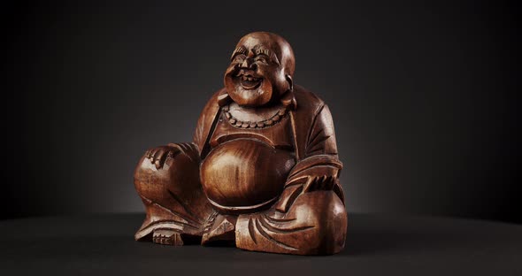 Rotating Wooden Buddha Over Black Background