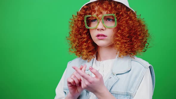 Young Thoughtful Redhead Woman in Eyeglasses and Panama Hat Counting on Fingers to Five Green Chroma