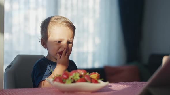 Happy Child Boy Eating Strawberries with Milk