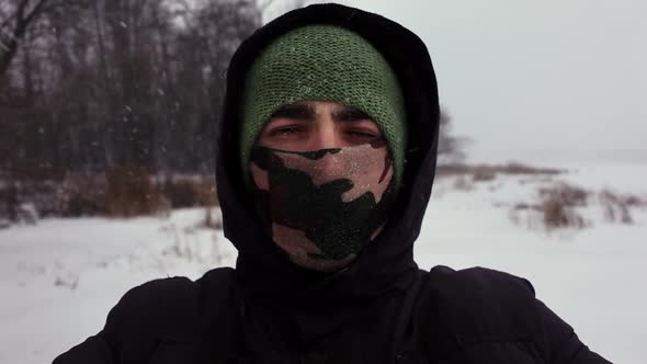 Selfie of Young Man Wearing Hood and Scarve Covering His Face Who Closes His Eyes Because of Snow