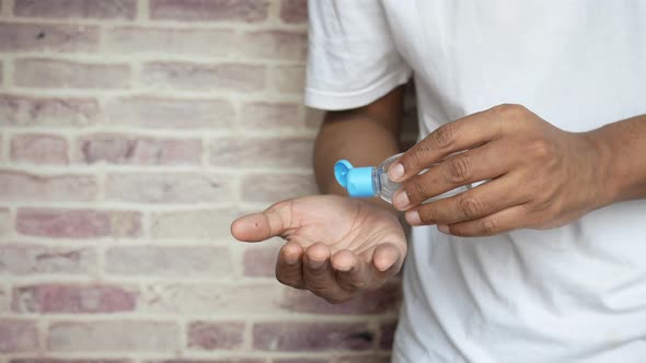 Young Man in Casual Dress Using Sanitizer Liquid While Standing