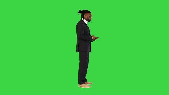 Black Man in Office Suit Typing Text on the Phone on a Green Screen Chroma Key