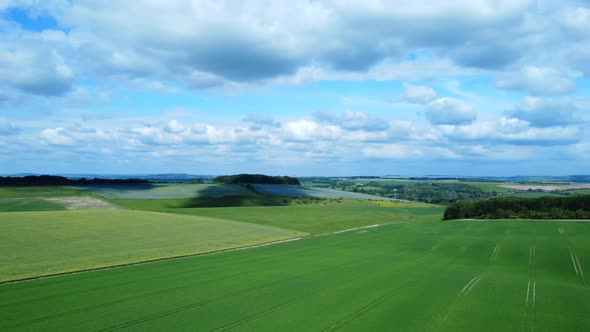 Aerial pan over green harvested farmland on Salisbury Plains in rural England