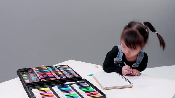 Child with sweet jeans with full set for painting and drawing practicing in notebook with white leav