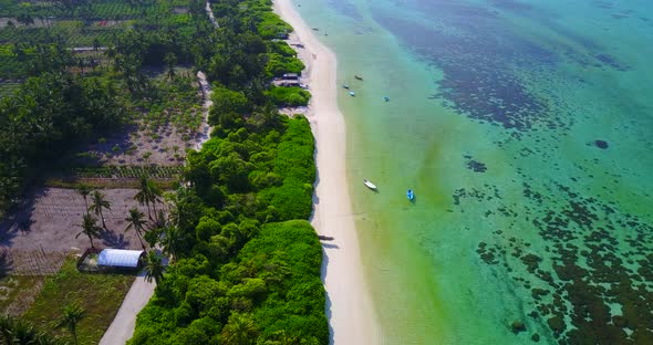 Daytime birds eye travel shot of a white sandy paradise beach and blue sea background in vibrant 4K