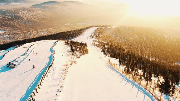 Aerial View of the Slopes and Slopes of the Ski Resort at Sunset Skiers and Snowboarders Roll Along