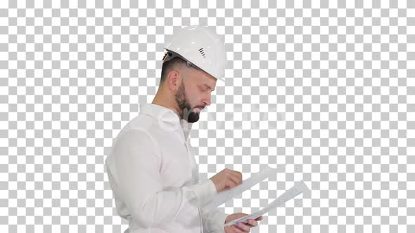 Male engineer walking in a hard hat looking at documents