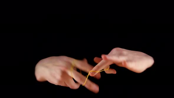 Magician Making Performance with Elastic on Black Background