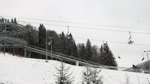 Chair Lifts Rodelbahn Alpine Coaster in Motion at Ski Resort on Winter Daytime Side View