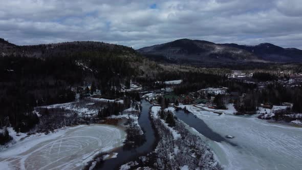 Aerial drone shot of landscape with water stream and mountains during winter in Ste-Émélie-de-l'Éner