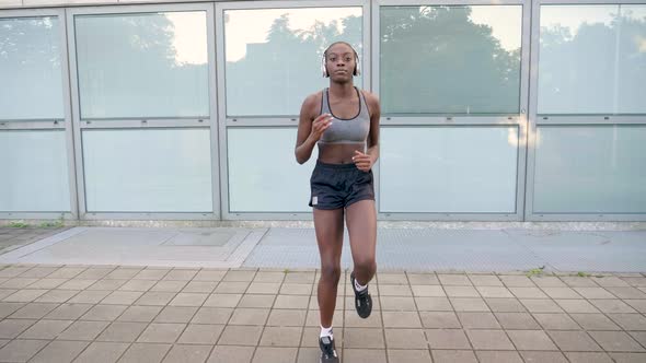 Slow motion shot of young woman with headphones jogging in place