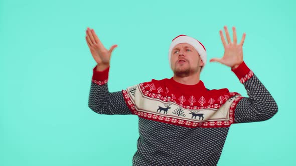 Young Adult Man in Sweater Santa Christmas Hat Jumps From Below Dancing Fooling Around Having Fun