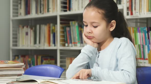 Cute Little Girl Dreaming While Reading a Book at the Library