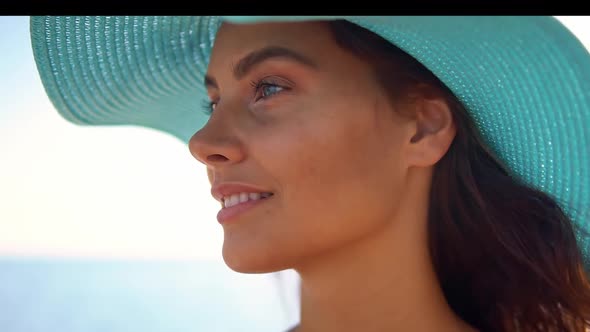 Portrait of Pretty Smiling Tanned Woman in Blue Straw Hat She Looks Forward While Driving the Yacht