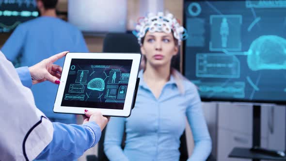 Female Doctor Looking at Tablet with Patient Brain Activity