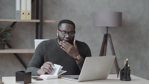 Tired African American Male Worker or Student Sit at Desk Sigh Yawn Feeling Stressed or Fatigue