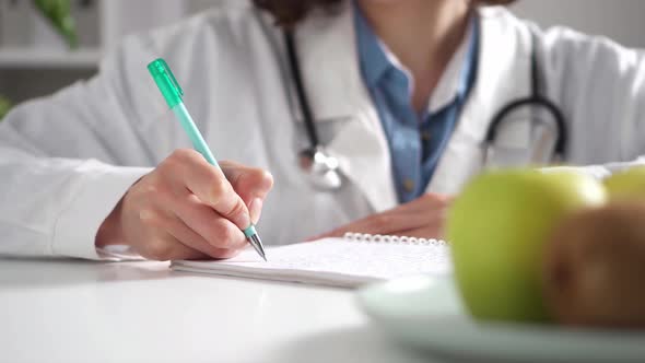 A Woman Doctor Sits At Her Desk Writes With A Pen In Ink Filling Out The Documentation Of A Medical