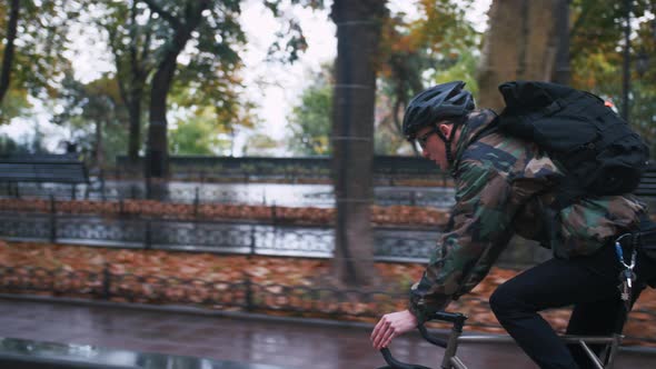Young Hipster Man in Helmet Riding Fixed Gear Bicycle in the City During Autumn Morning Side View