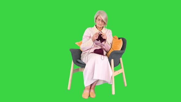 Intelligent Old Lady Knitting Sitting on a Chair on a Green Screen, Chroma Key