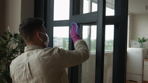 Quarantined chores. Man in a medical mask cleans windows during quarantine. 